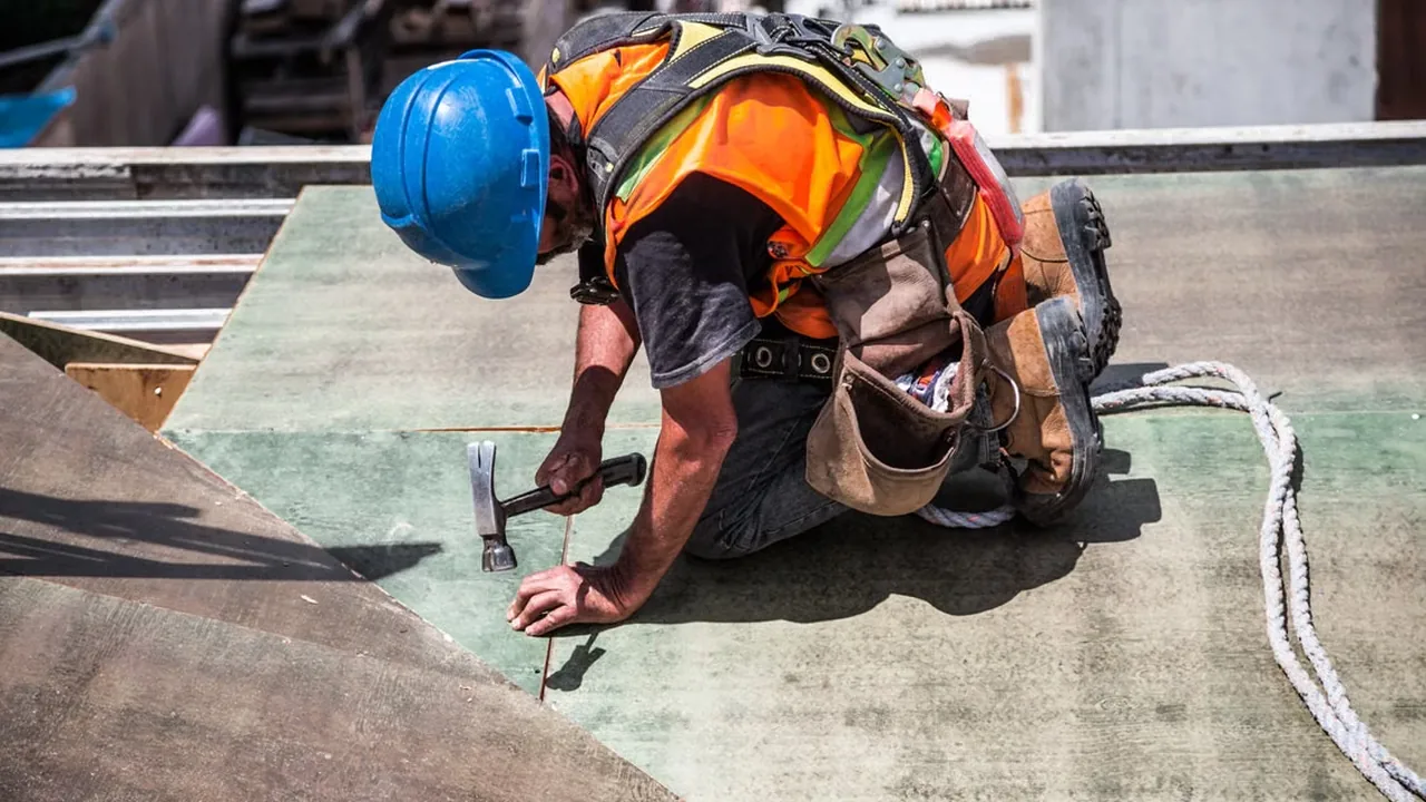 A roofer in a blue hard hat working on a roof