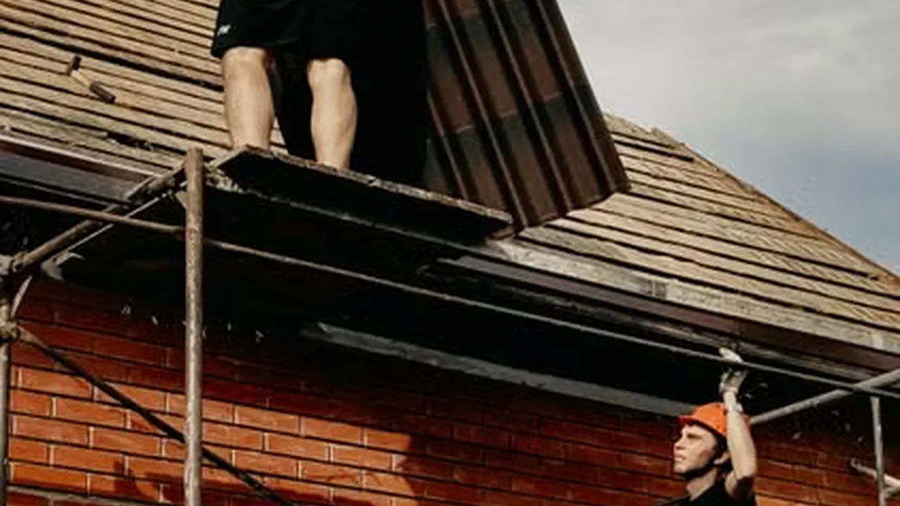 Roofing crew installing new roof panels from scaffolding